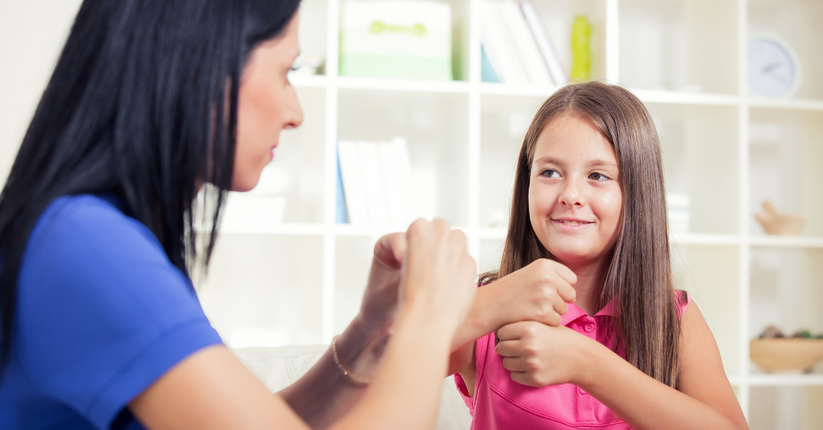 Una mujer y una niña comunicandose en lengua de señas.