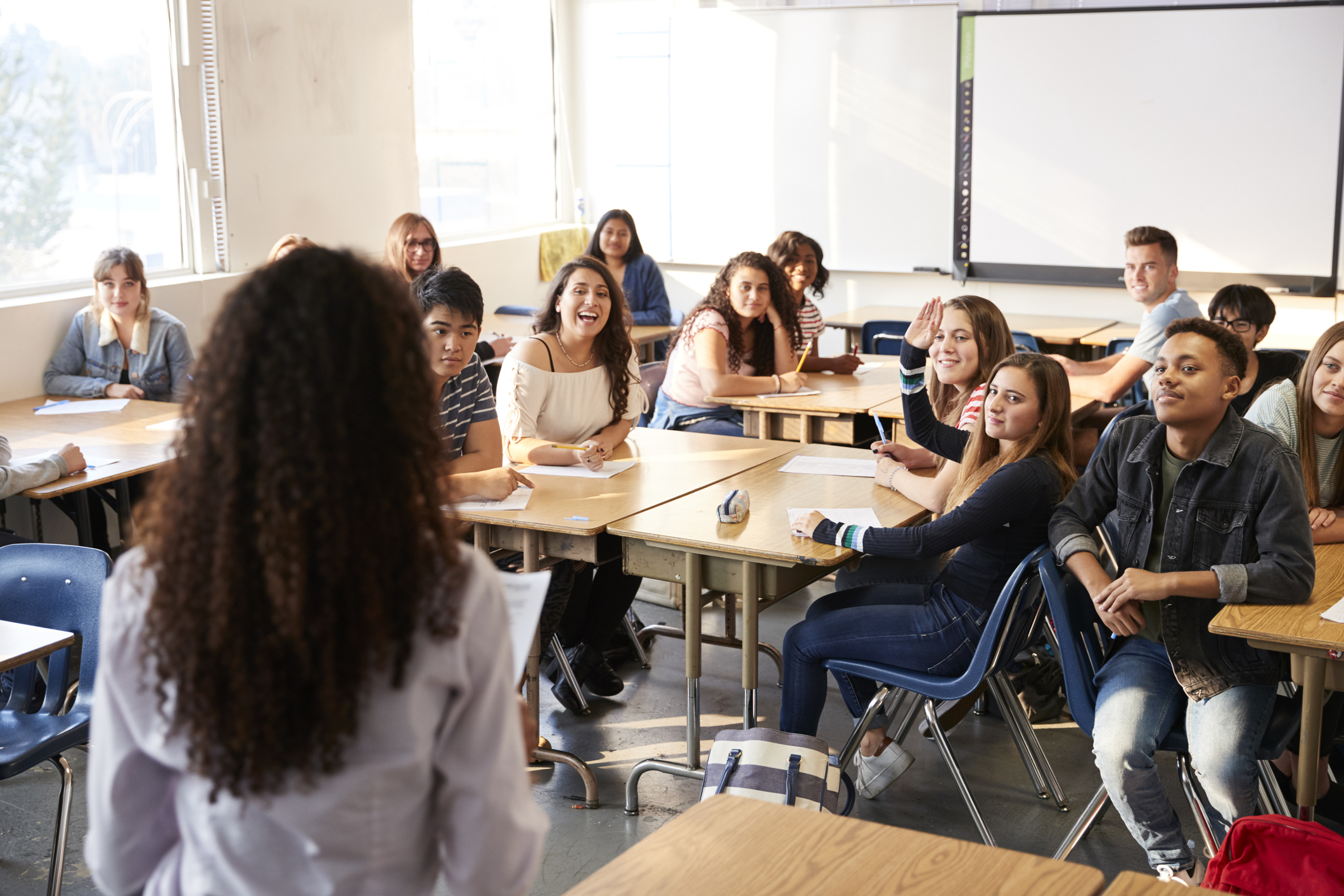 Rear View Of Female High School Teacher Standing At Front Of Class Teaching Lesson