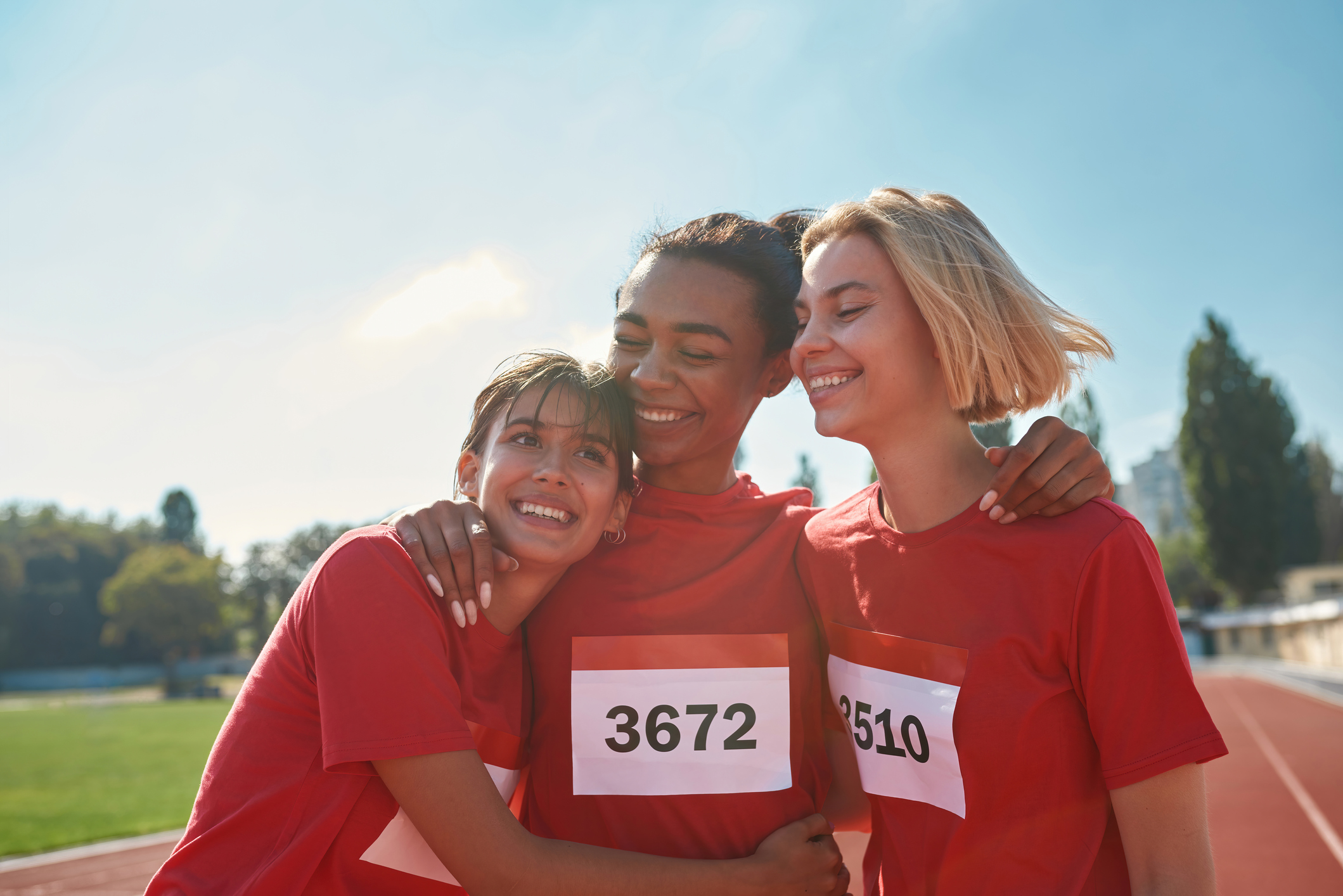 Portrait of young professional female runners wearing t shirts with number looking happy while standing together, ready for the race. Sports, active lifestyle, motivation concept